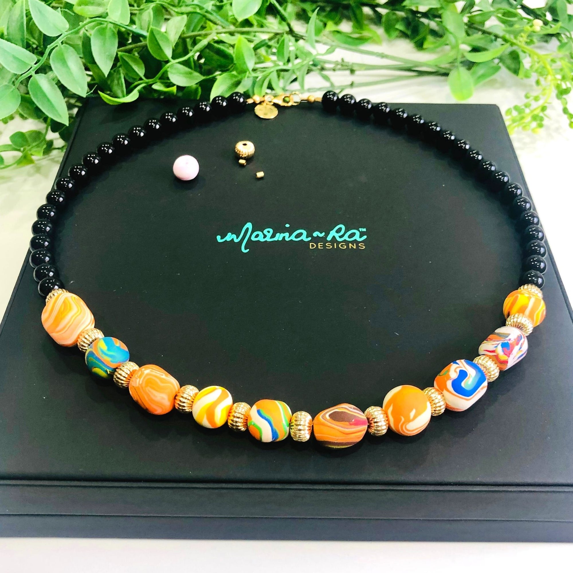 Handmade Beads, black onyx, quality  gold filled findings and Marina-ra insignia.  Beautiful Luxurious Packaging. Hand Assembled. Unique Gift.  Stunning Necklace. Orange, white, blue beads.  Trademark